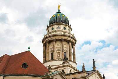 Low angle view of neue kirche against cloudy sky in city