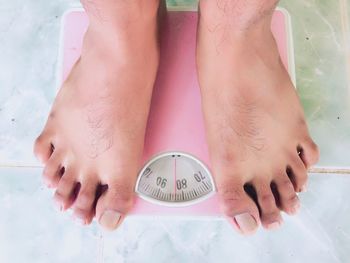 Low section of man standing on weight scale