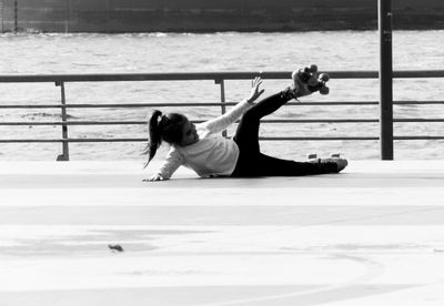 Girl falling on footpath against lake