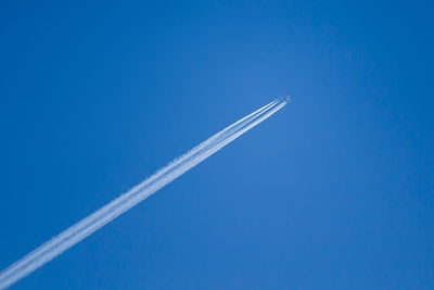 Low angle view of airplane flying against blue sky