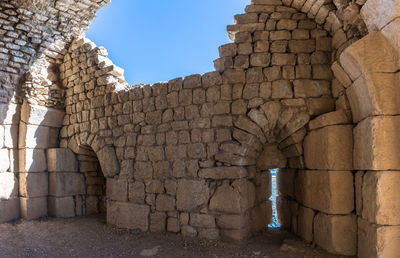 Stone wall of old building against sky