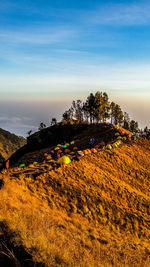 Tents on mountain against sky during sunset