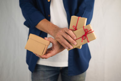 Midsection of man holding paper while standing against wall