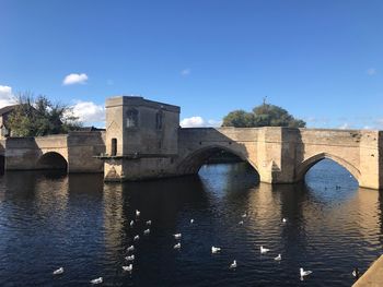 Arch bridge over river against clear blue sky