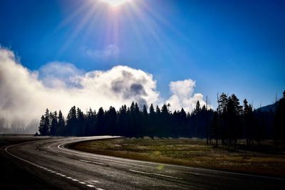 Road by trees against sky
