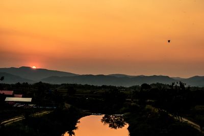 Scenic view of silhouette mountains against orange sky