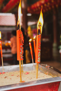 Lit tea light candles in temple against building