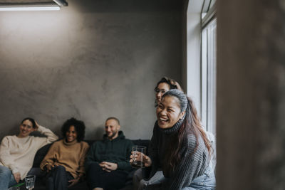 Cheerful businesswoman having coffee by colleagues while taking break in startup company