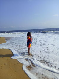 Woman standing at beach against sky