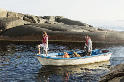 Family and dog on motorboat in baltic sea amidst rock formations