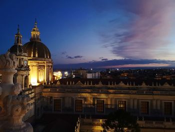 Illuminated buildings in city against sky at night