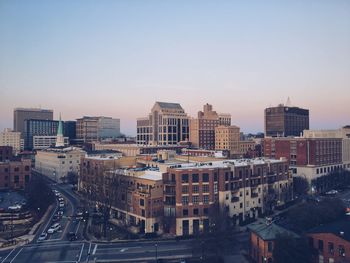 Buildings in city against clear sky during sunset