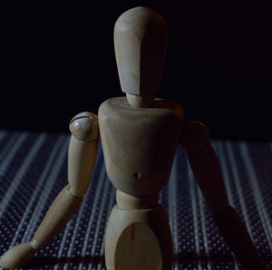 Close-up of wooden figurine against black background