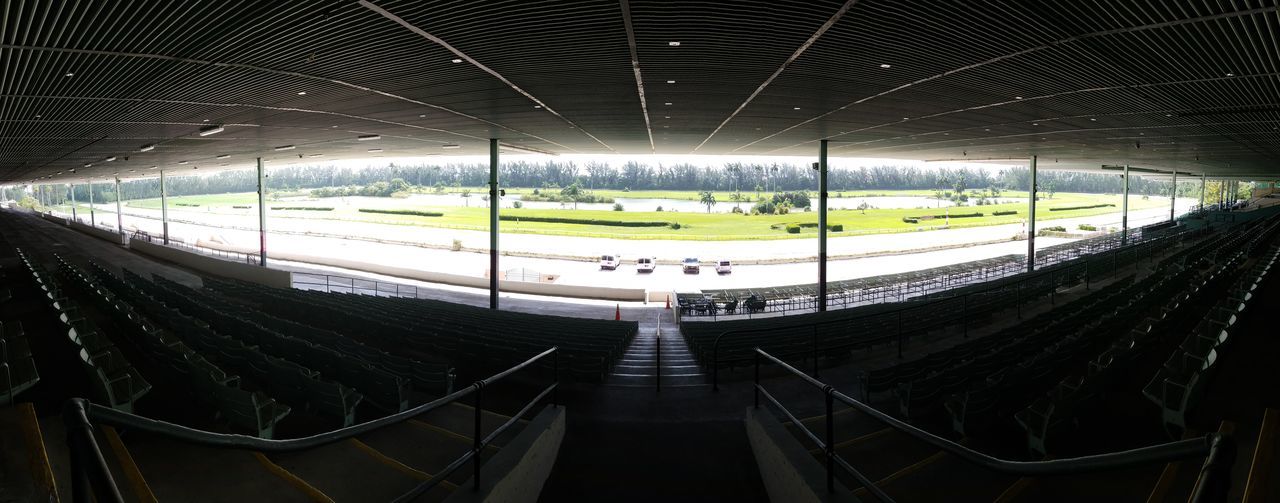 indoors, empty, architecture, illuminated, stadium, no people, transportation, seat, built structure, absence, ceiling, window, the way forward, direction, lighting equipment, diminishing perspective, nature, day, glass - material