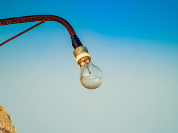 Low angle view of light bulb against clear blue sky