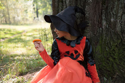 Midsection of woman holding umbrella on field in forest