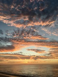 Scenic view of sea against dramatic sky during sunset