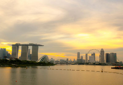 River by buildings against sky during sunset