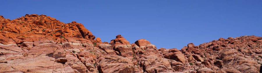 Low angle view of rock formation against clear blue sky