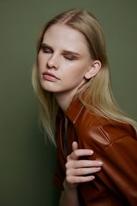 Portrait of young woman standing against wall