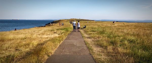 Rear view of father and son walking on footpath at cliff