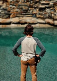 Rear view of man standing by sea during sunny day