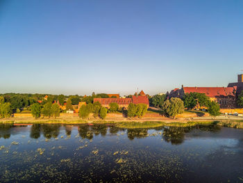 Scenic view of lake by buildings against clear blue sky