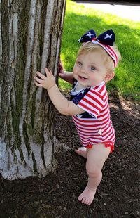 Portrait of cute girl standing on tree trunk