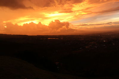 Scenic view of silhouette landscape against dramatic sky during sunset