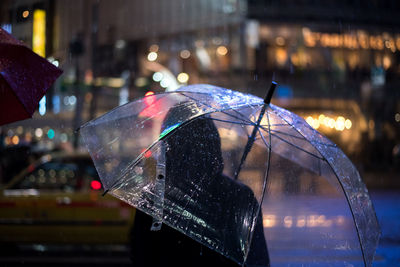Rear view of woman carrying umbrella at night