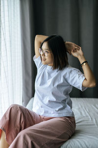 Young woman sitting on bed at home