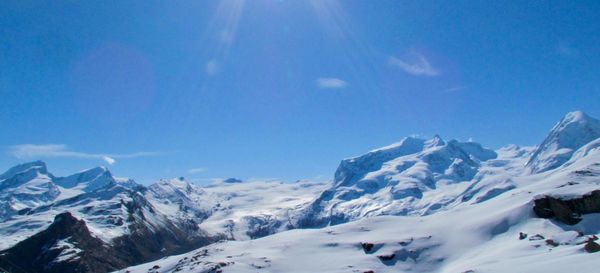 Scenic view of snowcapped mountains against blue sky