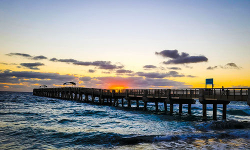 Pier over sea against sky during sunrise