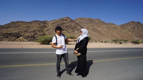 Young couple standing on road against mountain