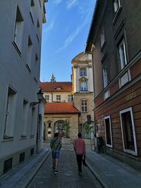 Rear view of people walking on street amidst buildings in city