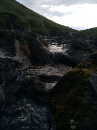 Scenic view of river flowing through rocks against sky