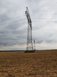 Low angle view of electricity pylon on field against sky