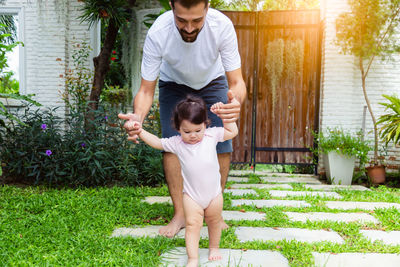 Full length of father and daughter walking on grass