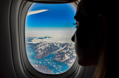 Close-up of airplane flying over landscape seen through window