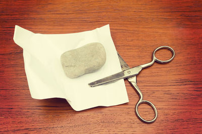 High angle view of stone and paper with scissors on table