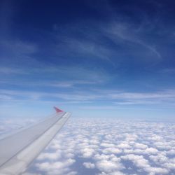 Airplane wing over clouds against sky