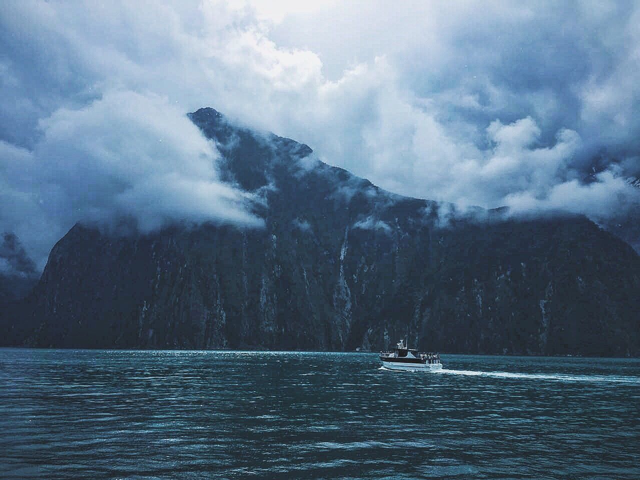 water, waterfront, mountain, tranquil scene, scenics, tranquility, beauty in nature, nature, lake, sky, cloud - sky, non-urban scene, mountain range, sea, calm, cloudy, outdoors, day, majestic, remote, solitude, no people, atmospheric mood