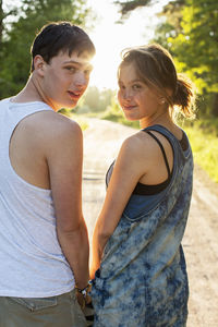 Rear view portrait of couple standing on dirt road