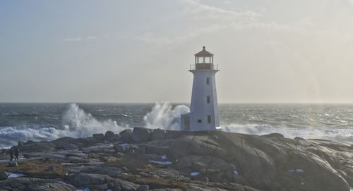 Lighthouse by sea against sky