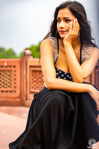 Portrait of young woman looking away while sitting outdoors