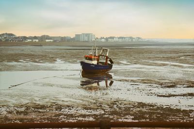 Boat moored on shore against sky