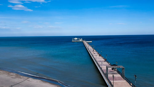 Pier over sea against blue sky