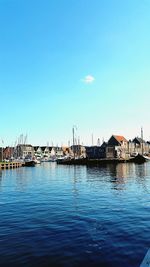 Sailboats moored at harbor against clear blue sky