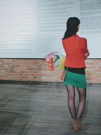Full length of woman standing against wall