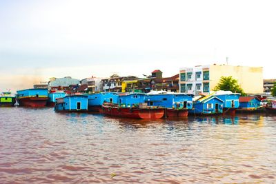 Boats moored at harbor against clear sky